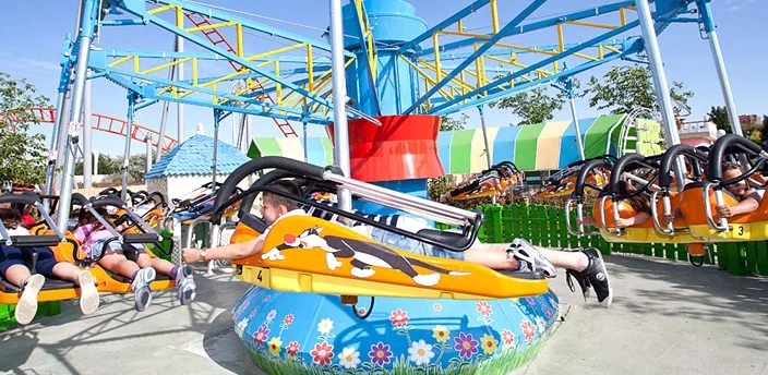 Niños tumbados sobre flotadores de colores en una atracción giratoria del Parque Warner