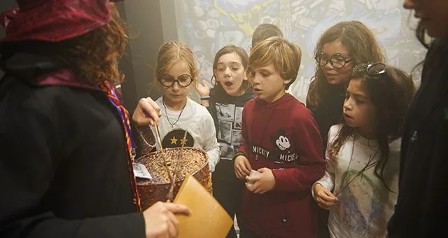 Grupo de niños alrededor de una monitora disfrazada durante una partida de escape room
