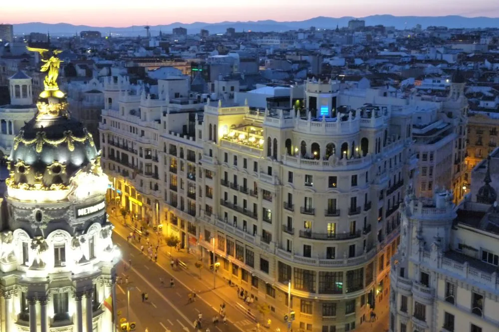 La Gran Vía al anochecer vista desde una azotea, con la cúpula del edificio Metrópolis a la izquierda