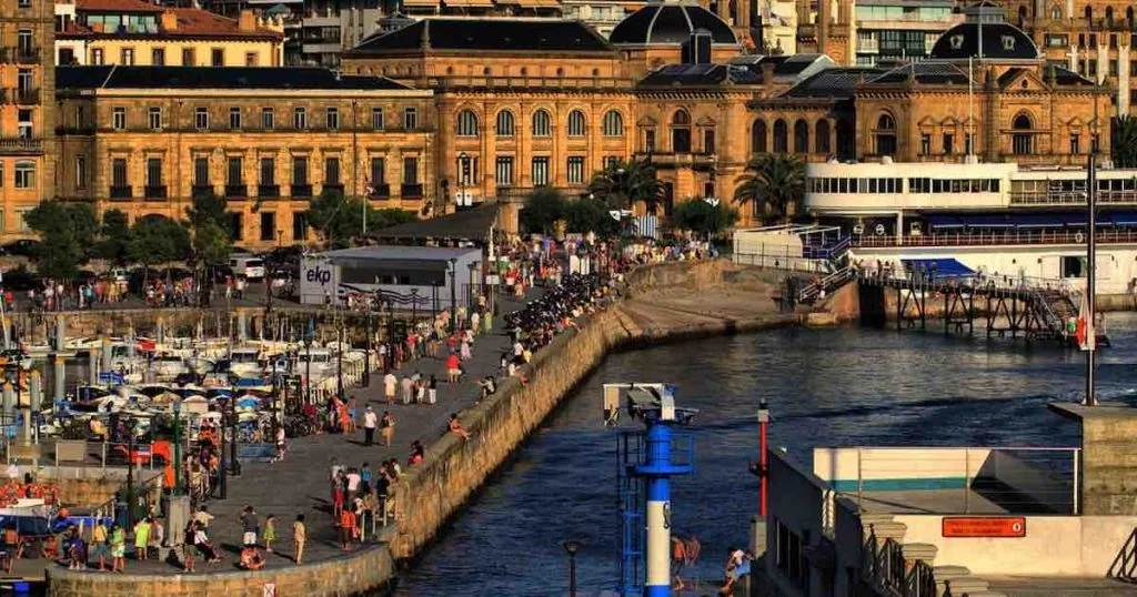 Paseo del puerto de San Sebastián lleno de gente, con los edificios señoriales del centro al fondo