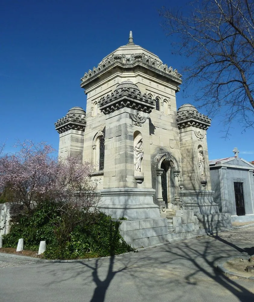 Panteón de piedra labrada del Cementerio de la Almudena, con un árbol en flor al lado