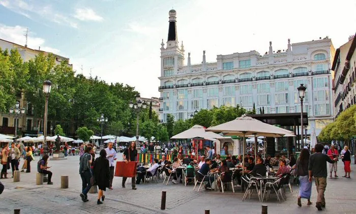 Terrazas llenas de gente en la Plaza de Santa Ana, con el edificio del hotel ME Reina Victoria al fondo