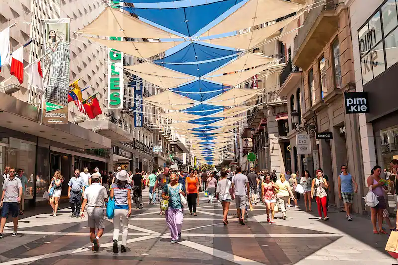 Gente paseando por la calle Preciados bajo los toldos triangulares, con el Corte Inglés a la izquierda