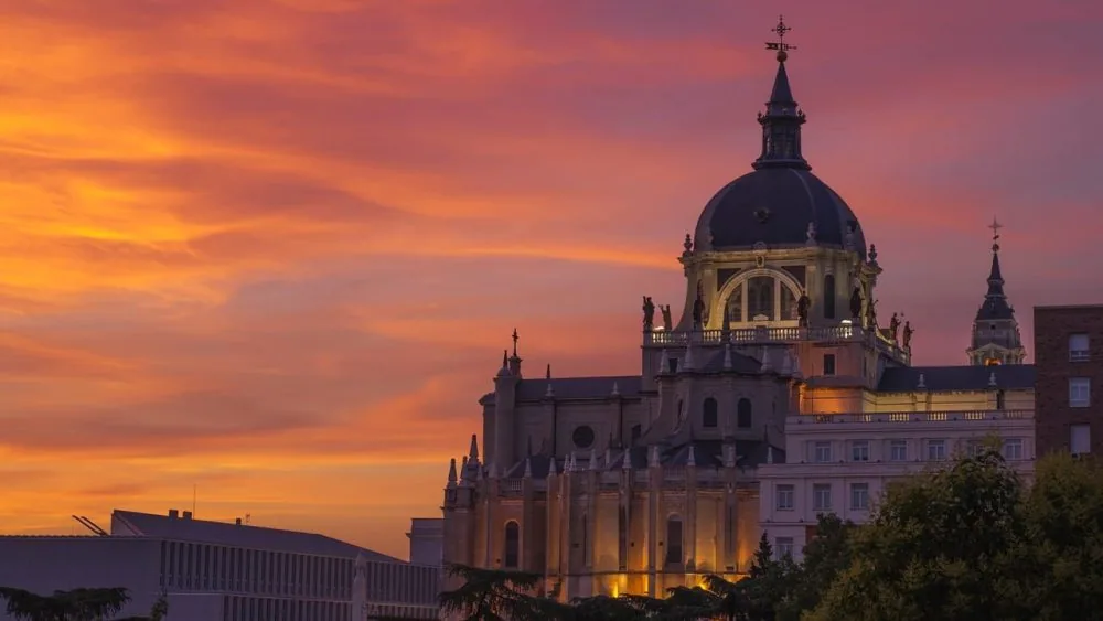 La cúpula de la Catedral de la Almudena recortada contra un cielo anaranjado al atardecer