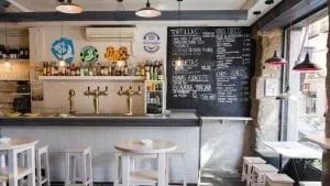 Interior de un bar de tapas con la barra, los tiradores de cerveza y la carta escrita en una pizarra