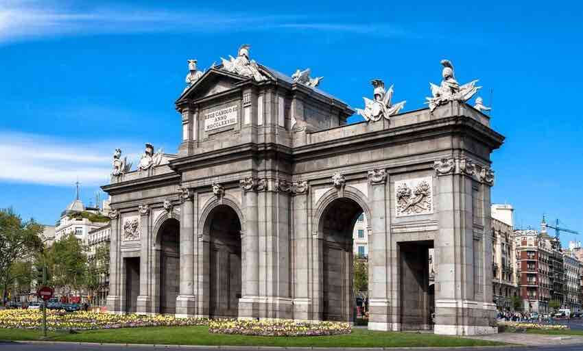 La Puerta de Alcalá con sus cinco arcos y un parterre de flores delante