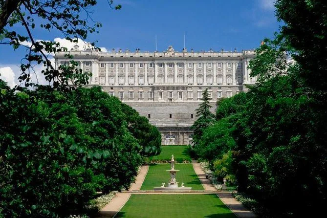 El Palacio Real visto desde el fondo de sus jardines, con una fuente en el eje central del césped