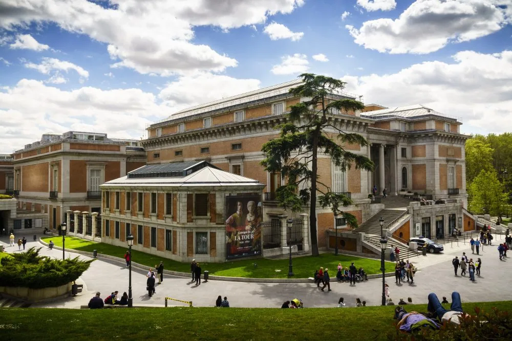 El edificio Villanueva del Museo del Prado visto desde el exterior, con gente paseando por la explanada