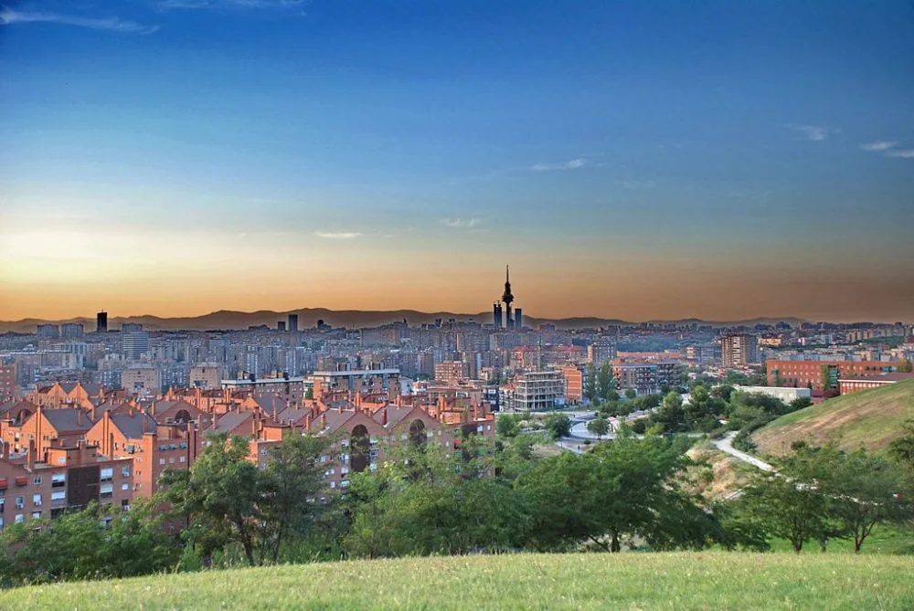 El perfil de Madrid al atardecer visto desde una loma de césped del Cerro del Tío Pío