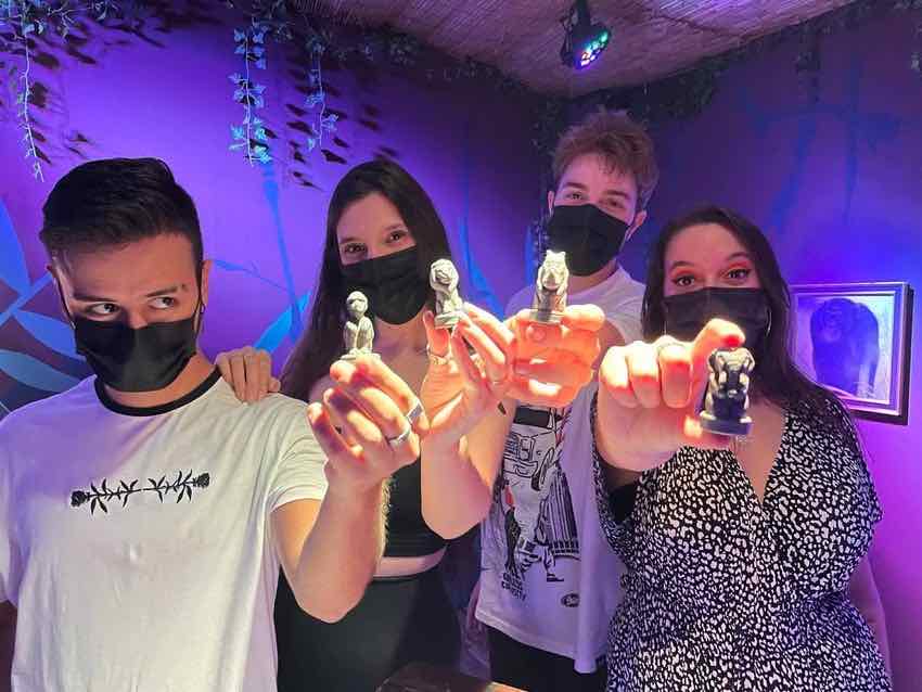 Cuatro jugadores mostrando las figuras que han encontrado en una sala de escape room