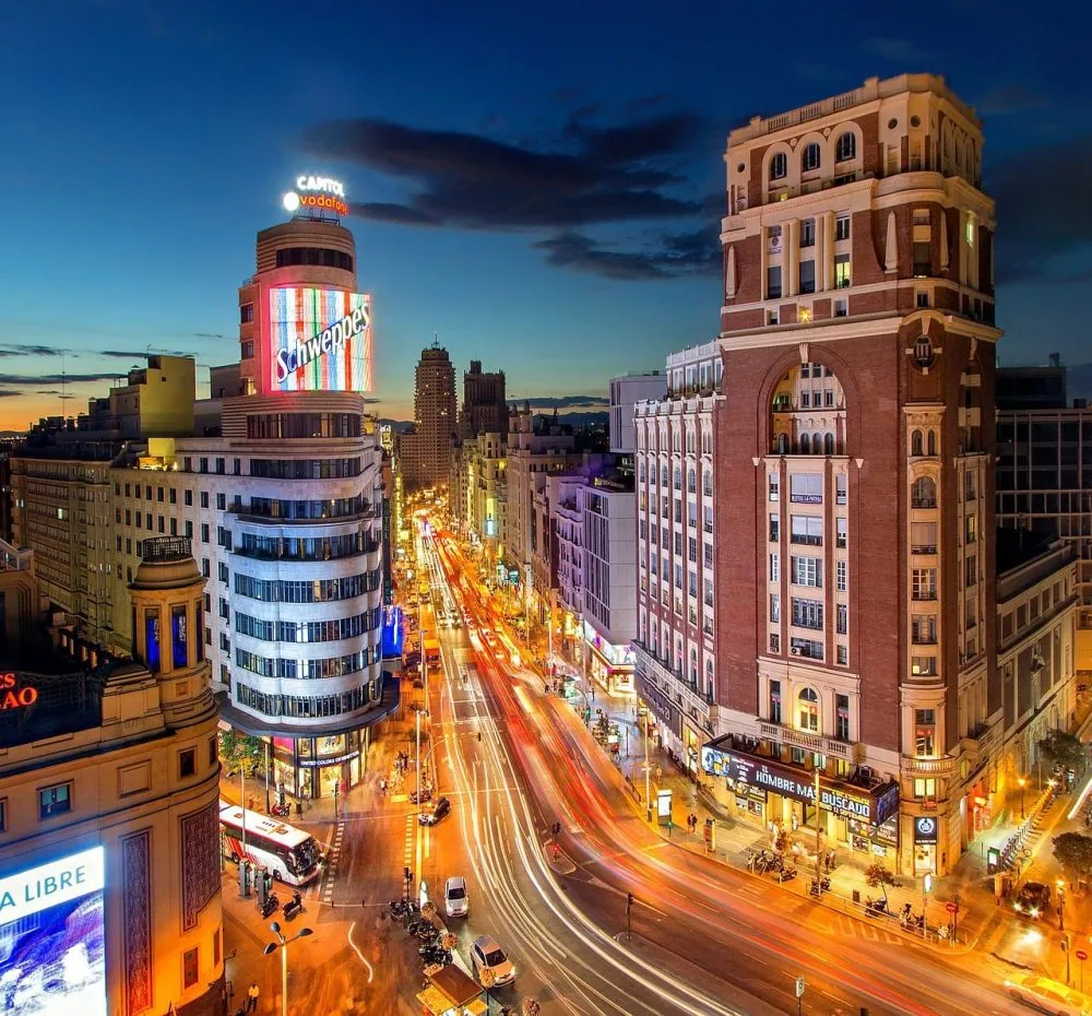 La Gran Vía de noche desde Callao, con el edificio Carrión iluminado y las estelas del tráfico