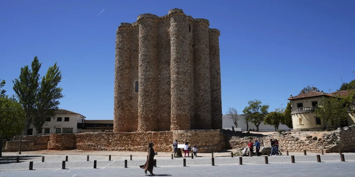 Torre del homenaje de piedra del castillo de Villarejo de Salvanés, con visitantes en la explanada